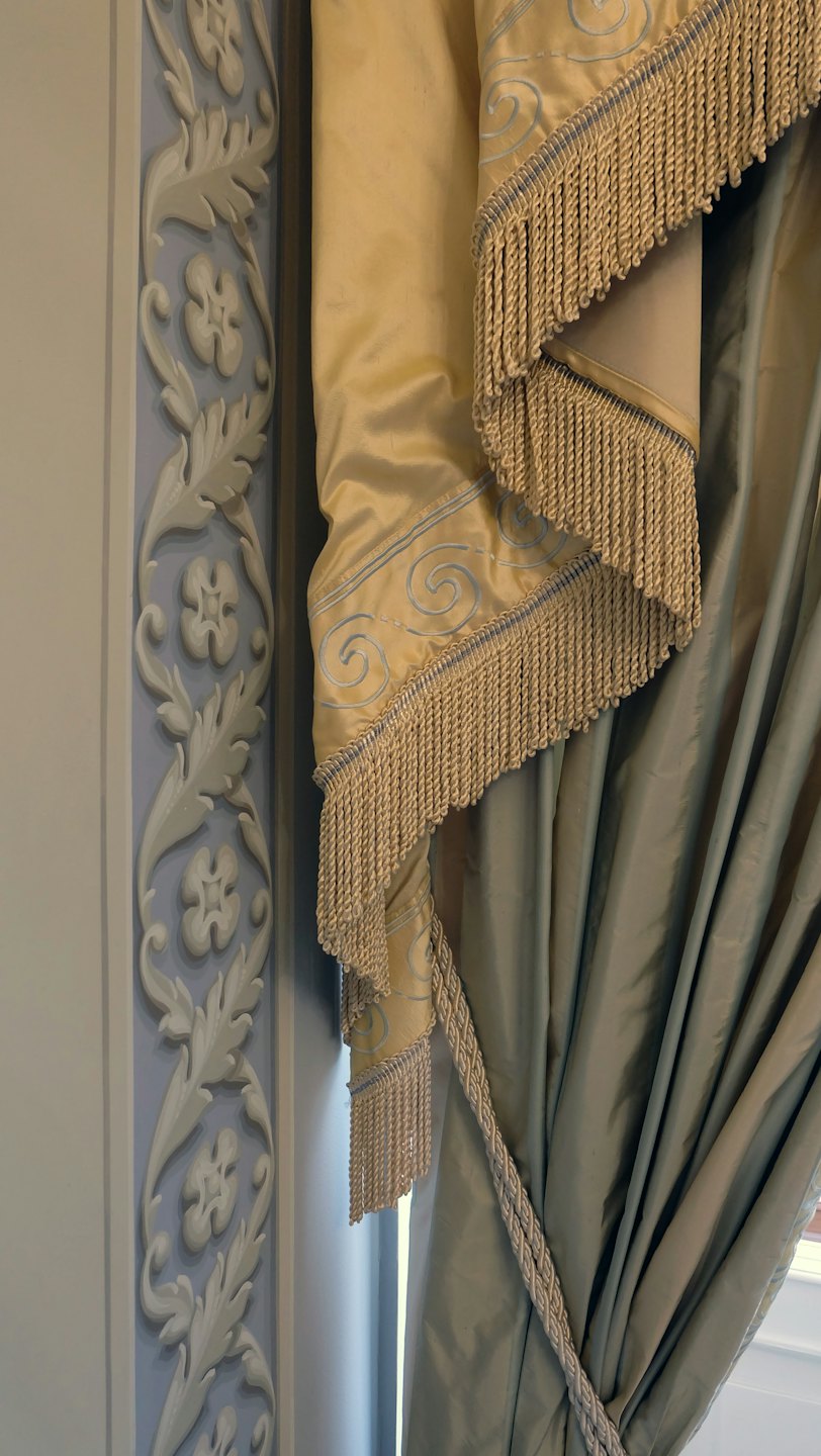 Eleganti tende dorate e verdi con modanature a muro ornate nelle vicinanze.