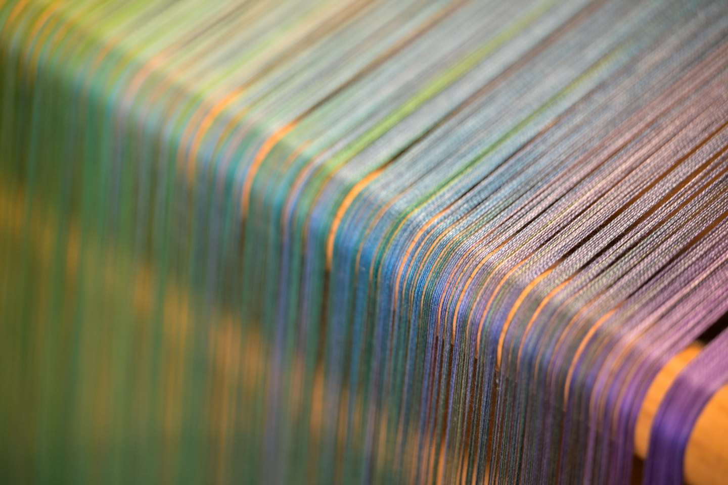 Fili di tessuto colorati tesi su tasselli di legno per la tessitura.